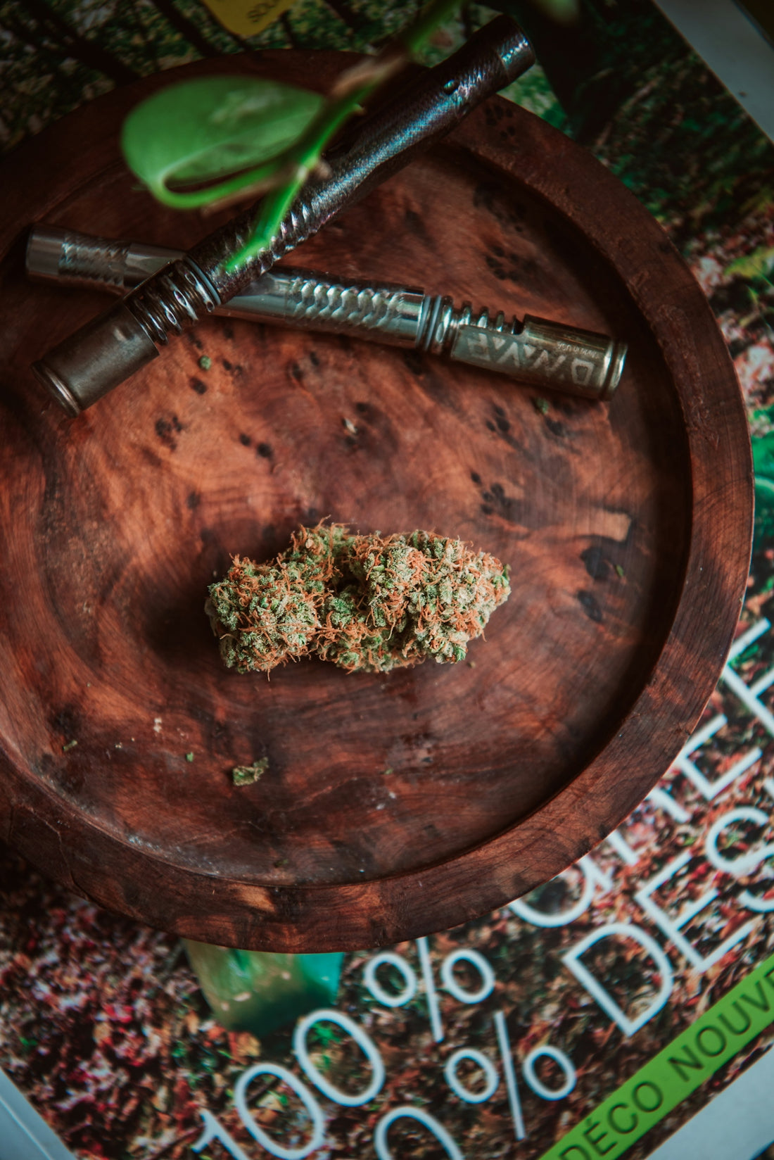 A cannabis bud and vaporizer are on a wooden plate.